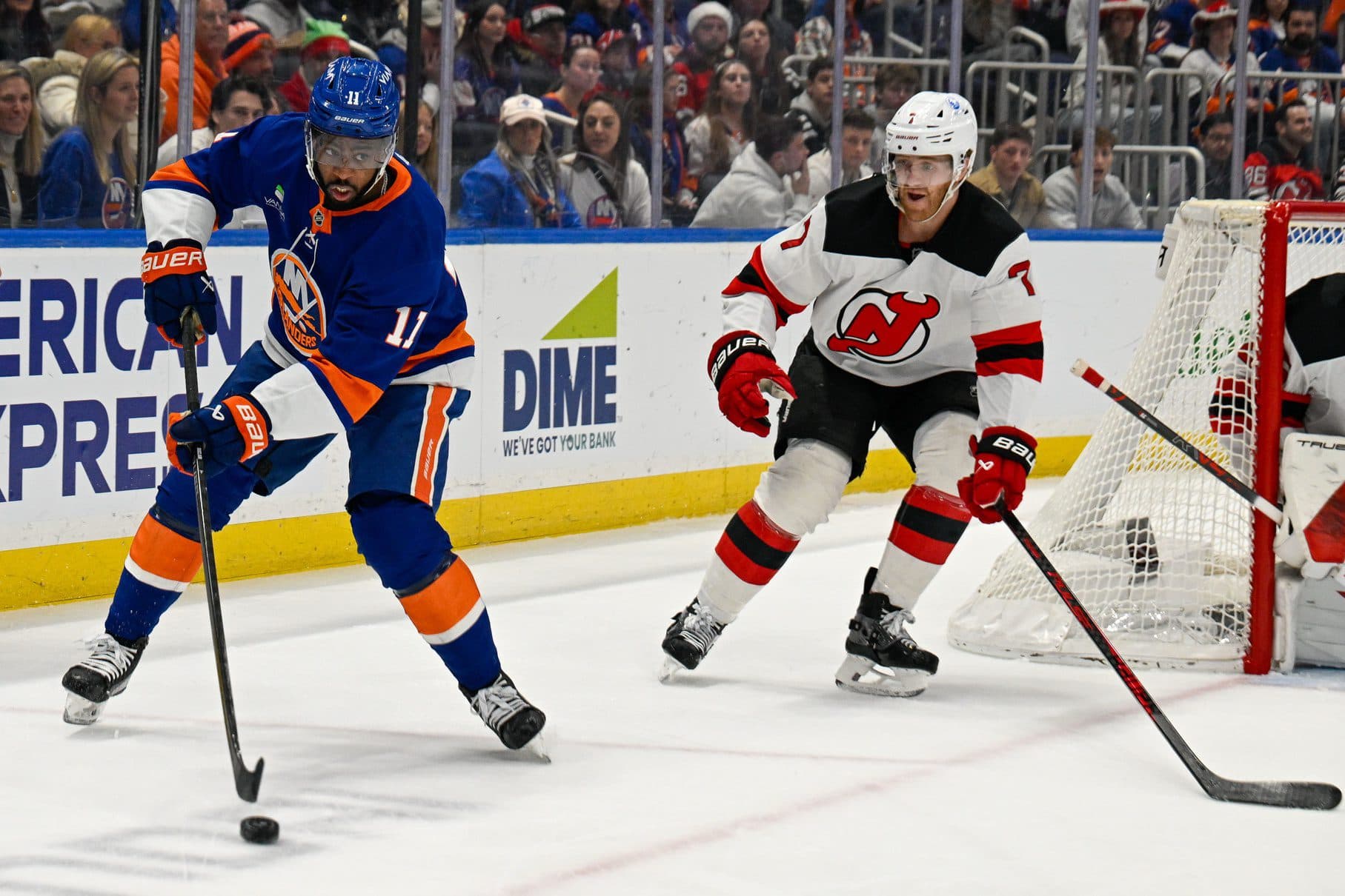 New York Islanders left wing Anthony Duclair (11) plays the puck from behind the net defended by New Jersey Devils defenseman Dougie Hamilton (7) during the second period at UBS Arena.