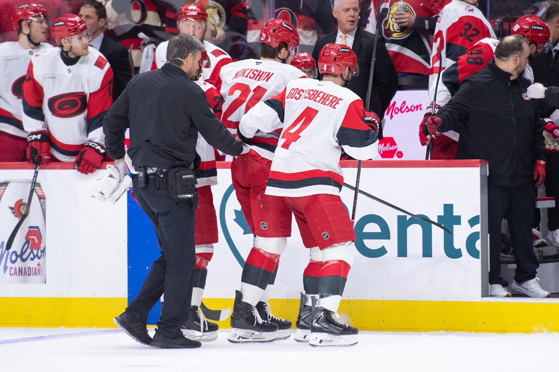 Carolina Hurricanes defenseman Alexander Nikishin (21) is escorted off the ice after being checked in the second period against the Ottawa Senators in game four of the first round of the 2026 Stanley Cup Playoffs at the Canadian Tire Centre.