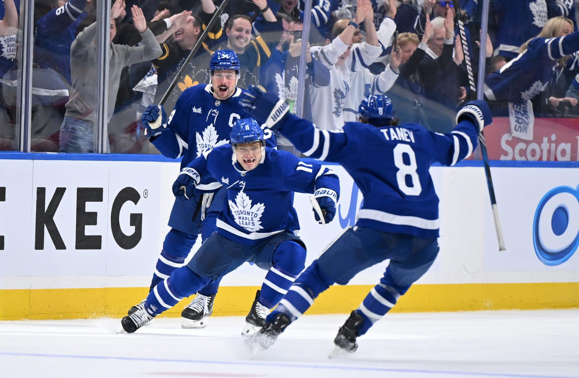 Toronto Maple Leafs forward Max Domi (11) celebrates with defenseman Chris Tanev (8) and forward Auston Matthews (34) after scoring the winning goal in overtime against the Ottawa Senators in game two of the first round of the 2025 Stanley Cup Playoffs at Scotiabank Arena