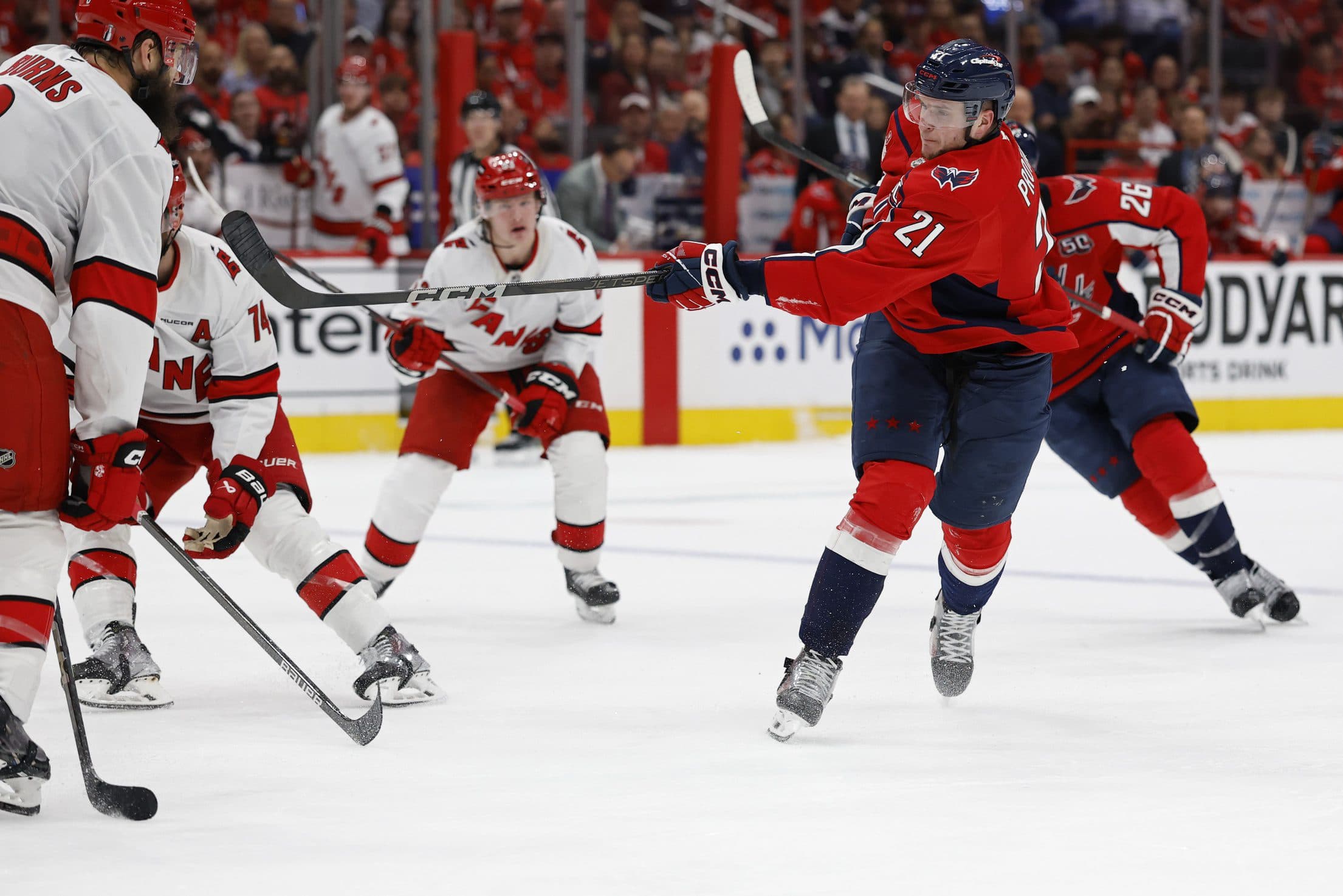 Washington Capitals center Aliaksei Protas (21) shoots the puck as Carolina Hurricanes defenseman Brent Burns (8) defends in the third period in game one of the second round of the 2025 Stanley Cup Playoffs at Capital One Arena.