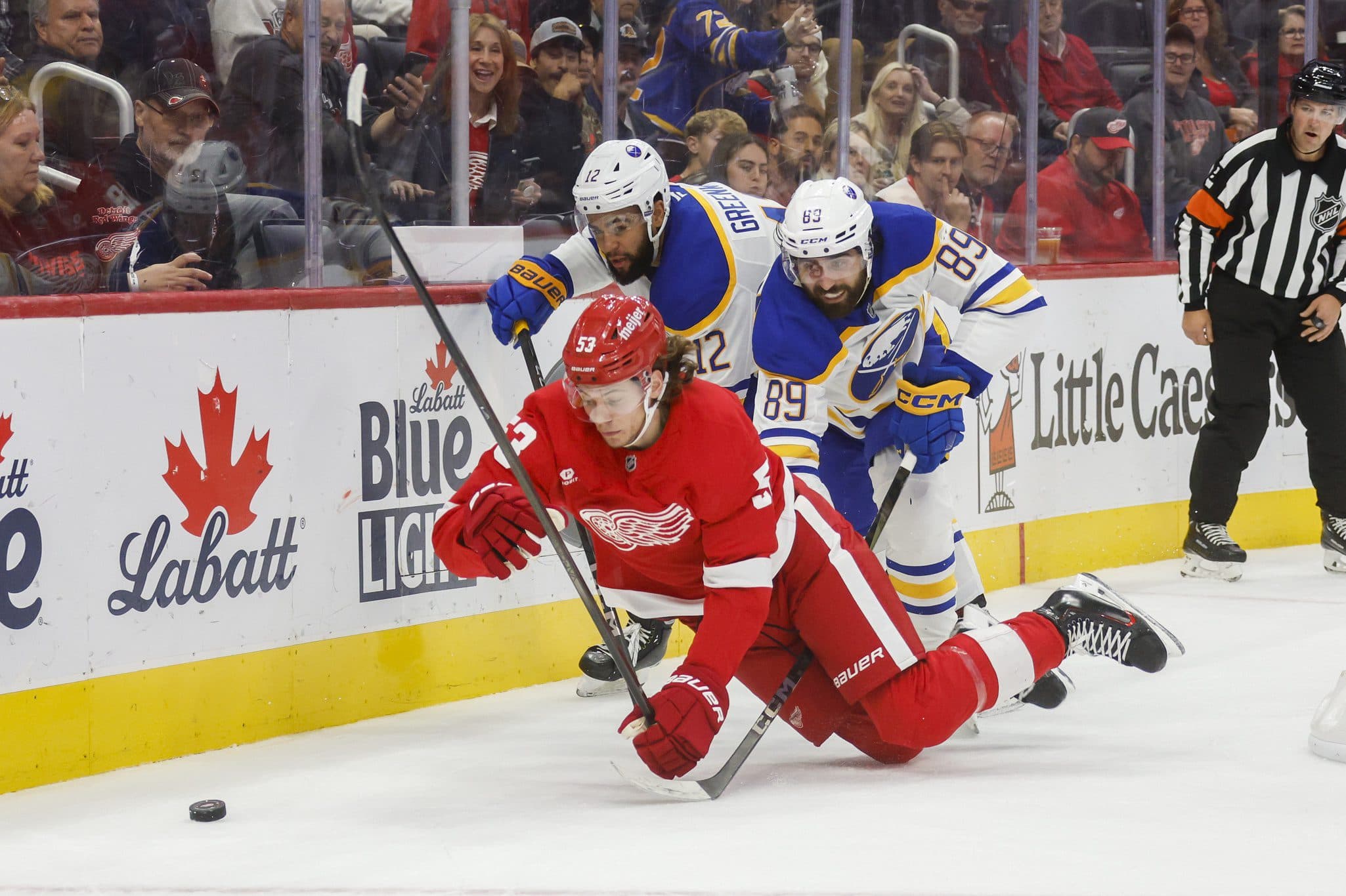 Detroit Red Wings defenseman Moritz Seider (53), Buffalo Sabres right wing Alex Tuch (89) and left wing Jordan Greenway (12) fight for control of the puck in the third period of the game at Little Caesars Arena.