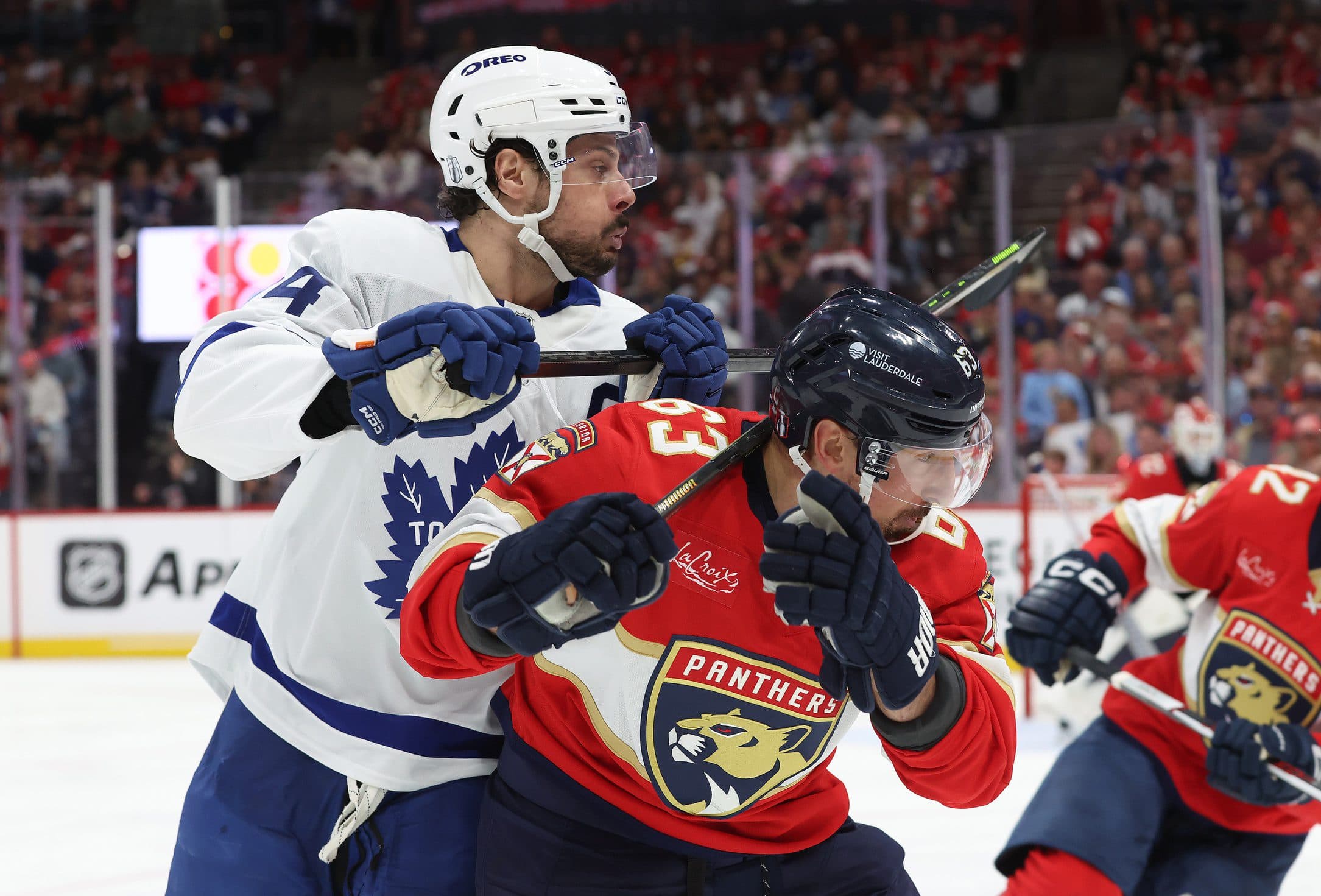 Toronto Maple Leafs center Auston Matthews (34) and Florida Panthers center Brad Marchand (63) fight to control the puck during the third period in game four of the second round of the 2025 Stanley Cup Playoffs at Amerant Bank Arena