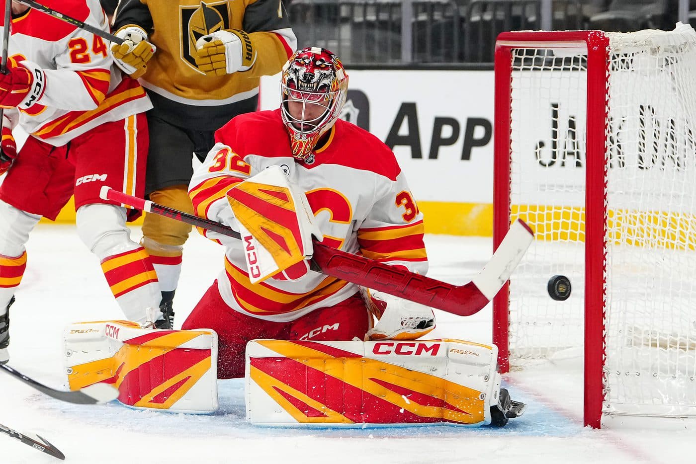 Calgary Flames goaltender Dustin Wolf (32) sweeps the puck away after making a save against the Vegas Golden Knights during the second period at T-Mobile Arena.