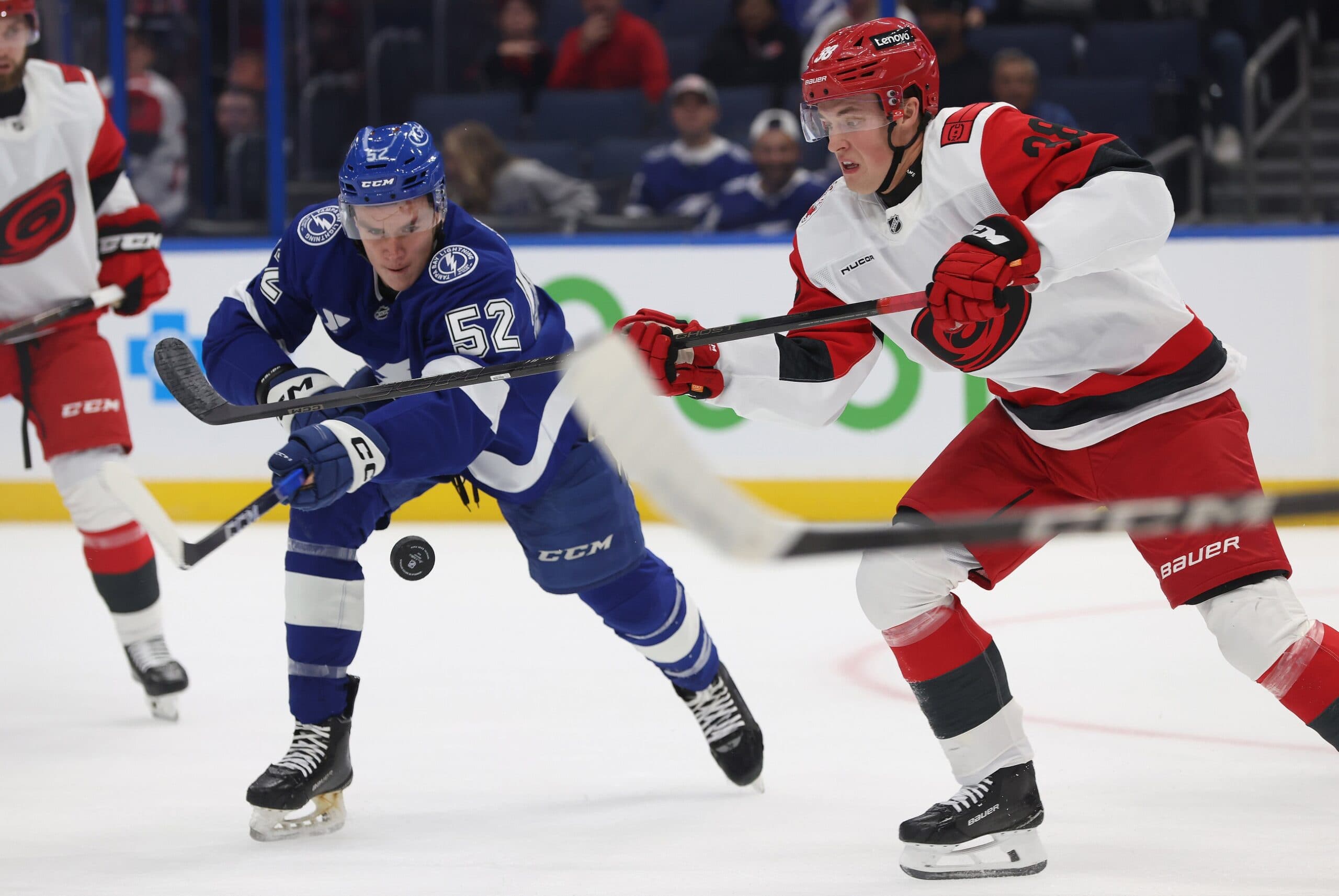 Tampa Bay Lightning defenseman Maxim Groshev (52) and Carolina Hurricanes right wing Noel Gunler (38) fight to control the puck during the first period at Benchmark International Arena.
